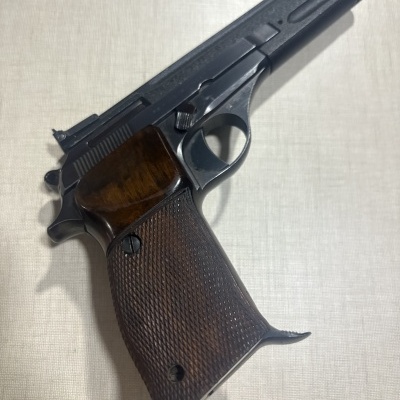 Pistola semiautomática com empunhadura em madeira castanha e estrutura metálica preta