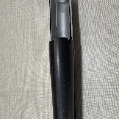 Tubo metálico preto com interior cinzento numa superfície de tecido bege claro