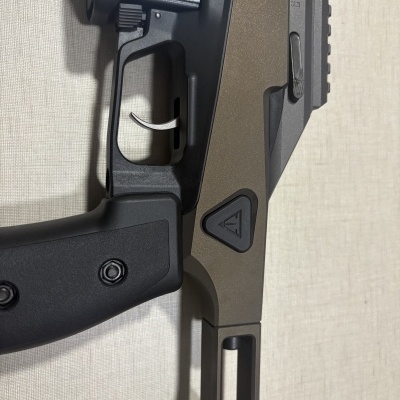 Parte de arma de fogo semi-automática com empunhadura preta e estrutura metálica cinza.