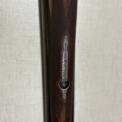 Coronha de rifle em madeira escura com gravações detalhadas e peça metálica ornamentada