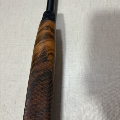 Cabo de um objeto em madeira e metal preto sobre superfície cinza