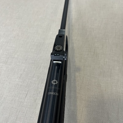 Arma de fogo preta com mira regulável e texto DRAGON vista de cima