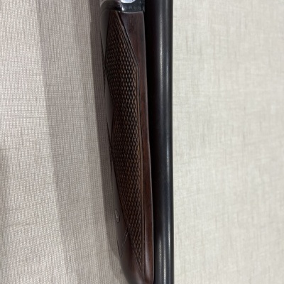 Espingarda de canos paralelos com empunhadura de madeira castanha trabalhada e detalhes metálicos prateados