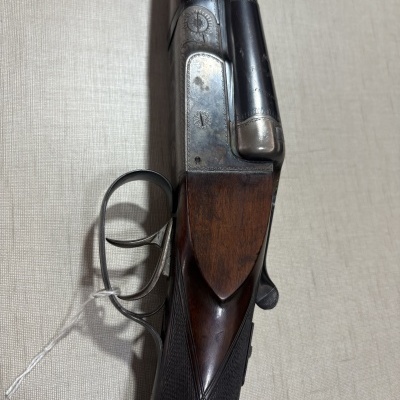 Espingarda de madeira e metal com gatilho duplo numa superfície bege