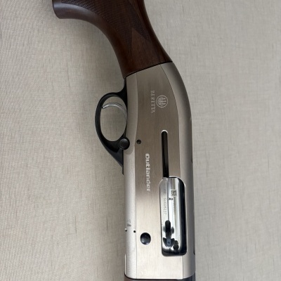 Espingarda Beretta Outlander com coronha em madeira castanha e corpo metálico prateado.