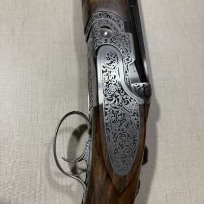 Espingarda de madeira e metal cinza com gravações ornamentais