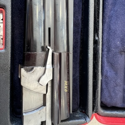 Arma de fogo cano duplo com inscrição MX8 dentro de estojo forrado a veludo azul escuro