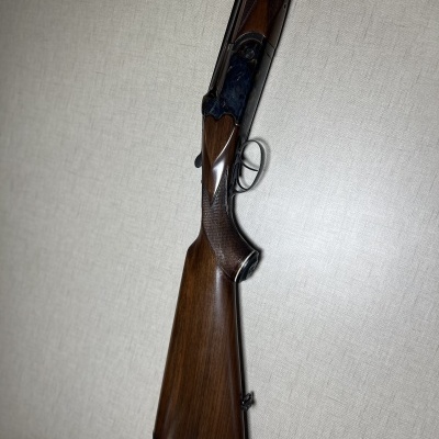 Espingarda de caça em madeira e metal sobre tecido bege