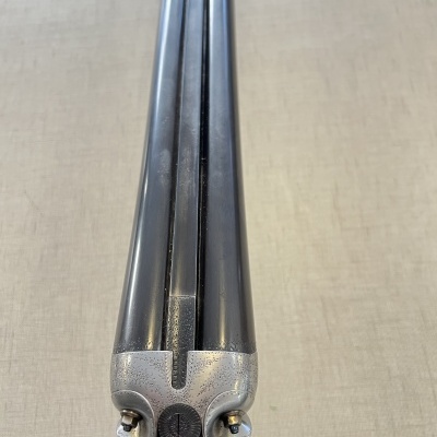 Escopeta de canos duplos em metal preto e aço prateado sobre superfície bege