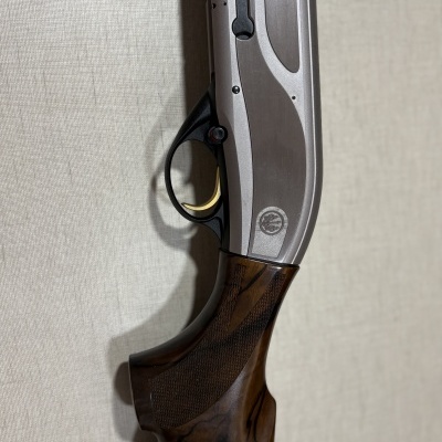 Espingarda de caça com madeira escura e metal prateado com texto e gravações