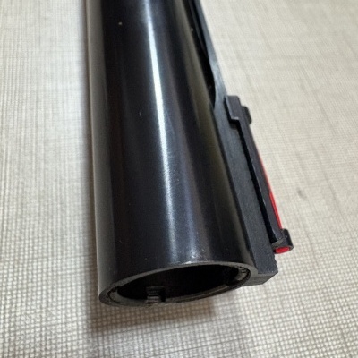 Objeto cilíndrico preto com acabamento liso sobre superfície têxtil bege