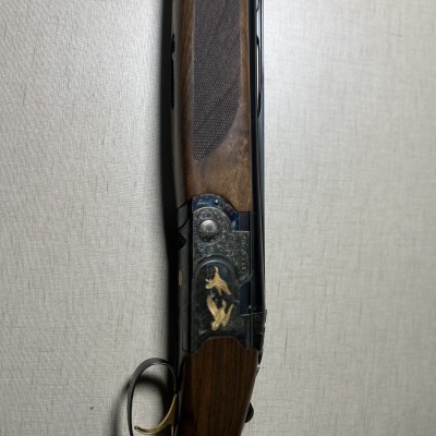 Espingarda de caça com punho de madeira e detalhes metálicos gravados.