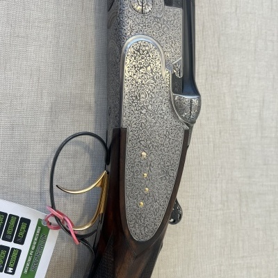 Espingarda de caça com gravações em metal prateado e madeira escura