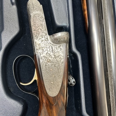 Espingarda de caça com detalhes gravados e madeira escura em estojo preto