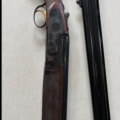 Arma de caça de cano duplo com empunhadura em madeira escura e canos em metal negro