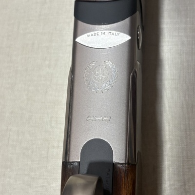 Parte superior de um arma de fogo com metal cinzento e punho em madeira castanha