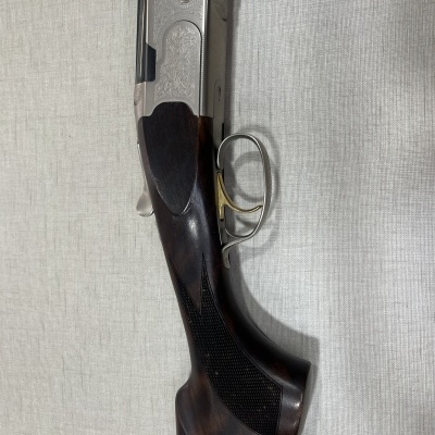 Espingarda com coronha em madeira escura e detalhe metálico prateado