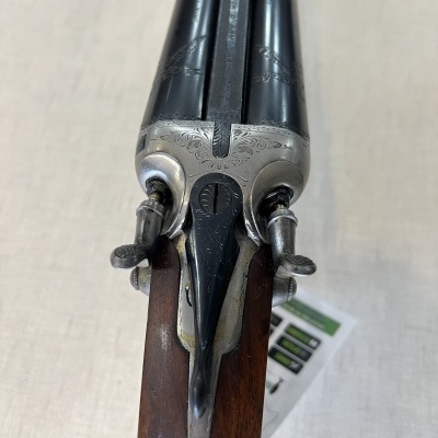 Espingarda dupla com canos pretos e cabo de madeira com detalhes gravados em metal