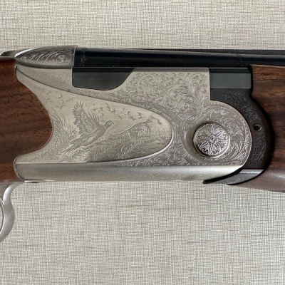 Arma de fogo com detalhes gravados em metal e coronha de madeira escura