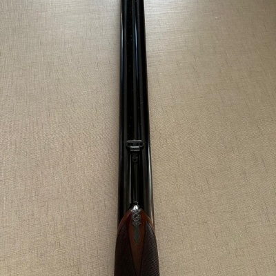 Espingarda de canos duplos paralelos em metal preto com empunhadura em madeira escura