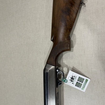 Espingarda de madeira e metal com etiqueta pendurada sobre fundo bege