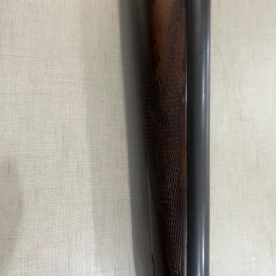 Pormenor de rifle com cano metálico e coronha de madeira texturizada