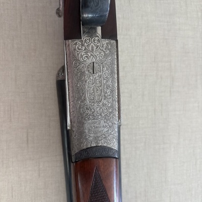 Parte superior de uma espingarda com madeira castanha e metal gravado