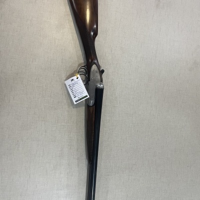 Espingarda com coronha de madeira castanha e canos pretos pendurada na parede