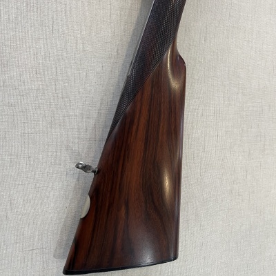 Coronha de madeira escura de espingarda com padrão xadrez e fundo cinzento