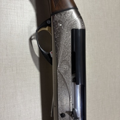 Espingarda com coronha de madeira, detalhes em metal prateado gravado e peça preta lisa