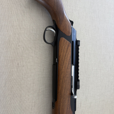 Detalhe de arma de fogo com madeira castanha e estrutura metálica preta