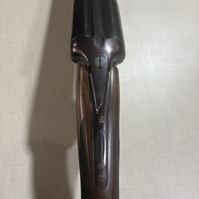 Espingarda de canos paralelos com coronha em madeira castanha e metal escuro vista de cima