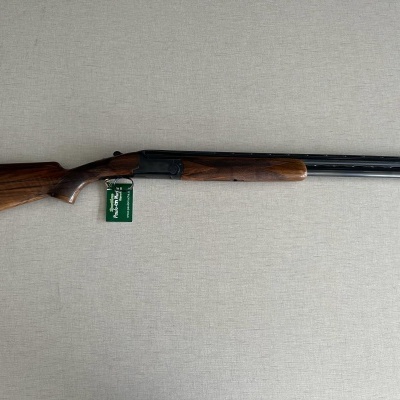 Espingarda de canos duplos em madeira e metal sobre superfície cinzenta