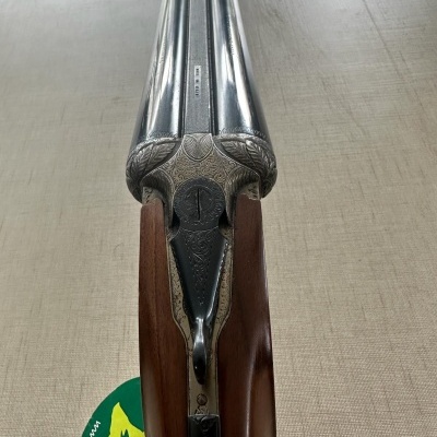 Espingarda de canos paralelos com detalhes gravados e empunhadura de madeira