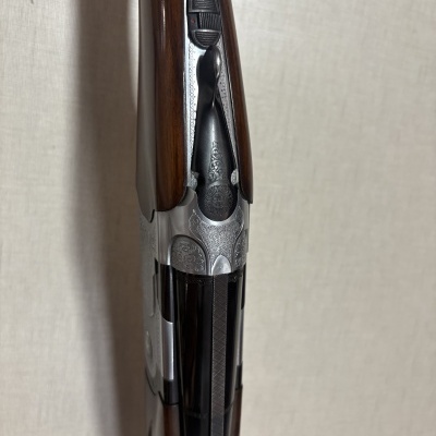 Parte central de arma de fogo com madeira castanho escuro e detalhes metálicos gravados