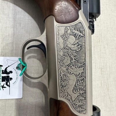 Espingarda de caça com empunhadura de madeira e detalhes metálicos gravados