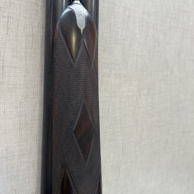 Espingarda de cano duplo com punho em madeira escura e padrão geométrico