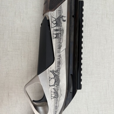 Espingarda com detalhes em madeira e metal prateado, gravações de veados, texto gravado na arma, fundo branco texturizado.