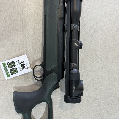 Espingarda verde com mira telescópica preta sobre fundo cinzento