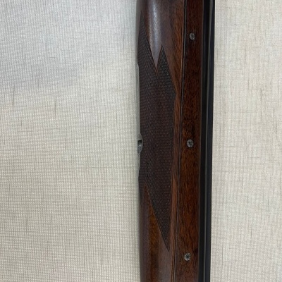 Parte dianteira de espingarda em madeira escura com detalhes em metal gravado