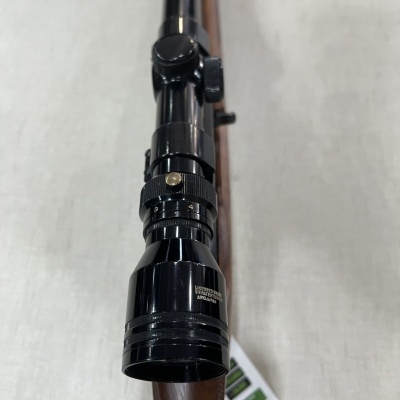 Rifle com luneta preta e coronha de madeira.