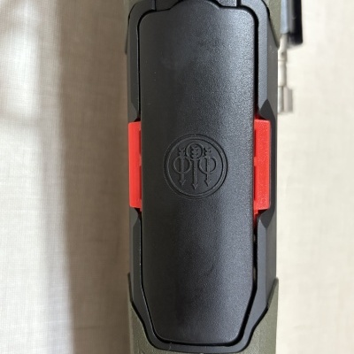 Parte superior de ferramenta com botão preto, detalhes vermelhos e corpo verde texturizado