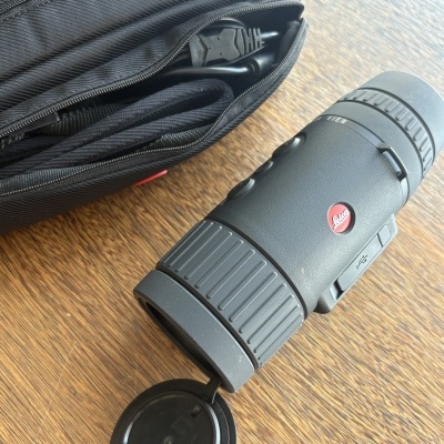 Monóculo ou telescópio preto com tampa aberta e bolsa preta com cabo USB