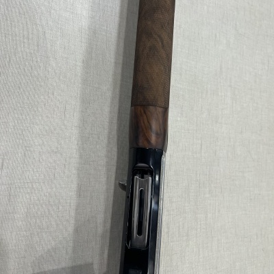 Cano de arma de fogo com cabo de madeira e corpo metálico preto