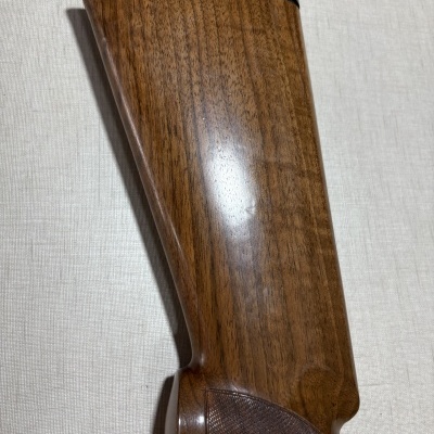 Ponteira de arma de fogo de madeira castanha e borracha preta sobre fundo bege