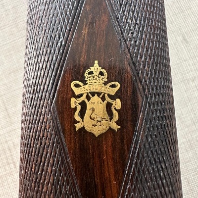 Madeira escura com padrão em relevo e brasão dourado com texto 1885 SE.