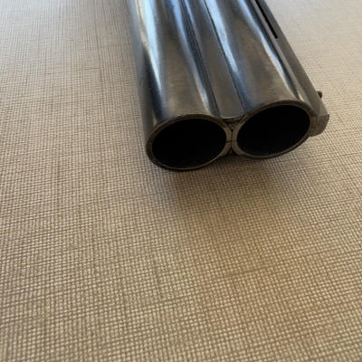 Canos duplos de espingarda preta de metal sobre superfície bege texturizada