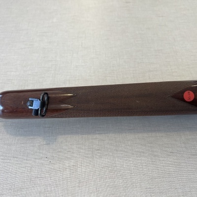 Arma de pressão com coronha em madeira escura e mira traseira