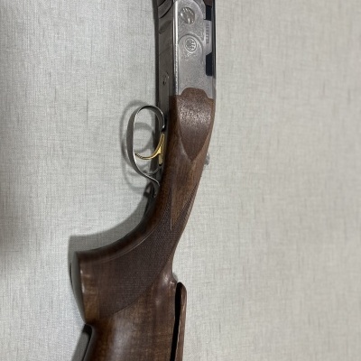 Espingarda com coronha de madeira escura e partes metálicas prateadas