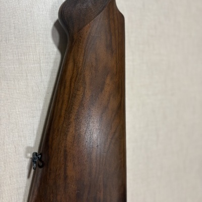 Coronha de espingarda em madeira castanho escuro com textura quadriculada no topo